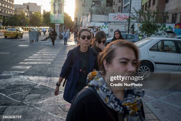 Young Iranian women without wearing mandatory headscarves cross a street in downtown Tehran, September 12, 2023.