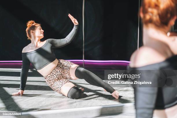 young red haired woman in sportswear dancing against mirror in the studio - pole dancing class stock pictures, royalty-free photos & images