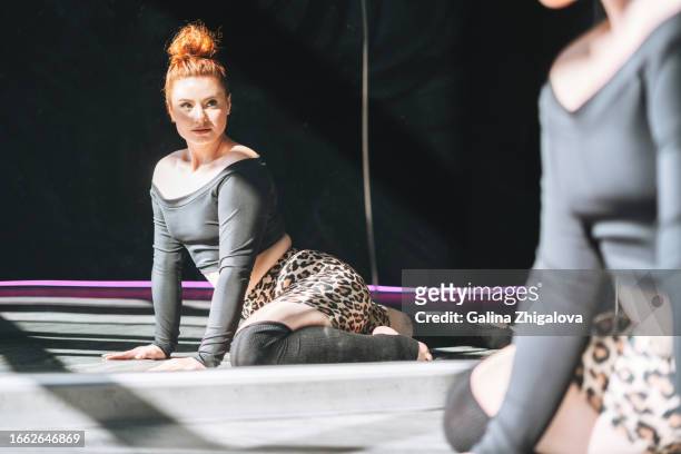 young red haired woman in sportswear dancing against mirror in the studio - pole dancing class stock pictures, royalty-free photos & images