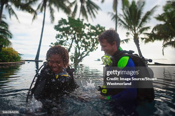 scuba divers splashing in water - fiji people stock pictures, royalty-free photos & images