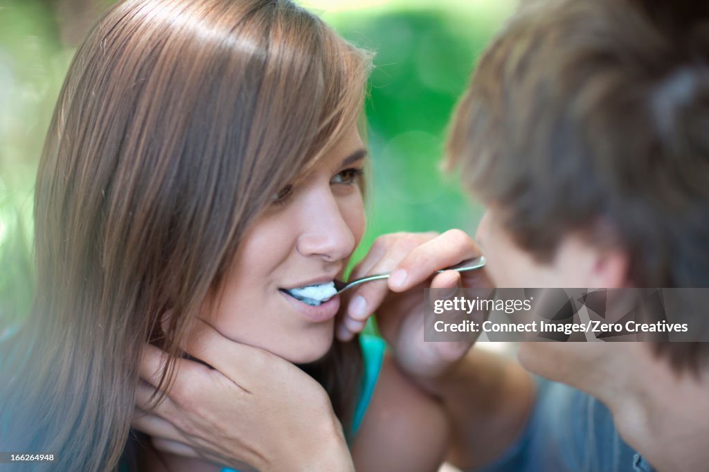 Man feeding girlfriend outdoors