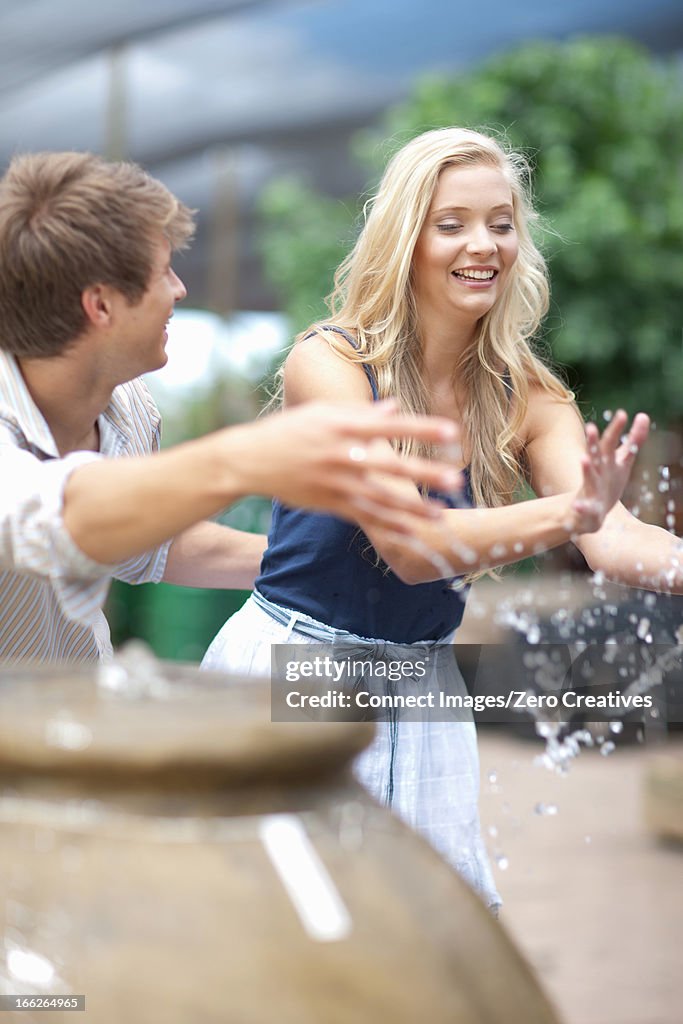 Man splashing girlfriend in fountain