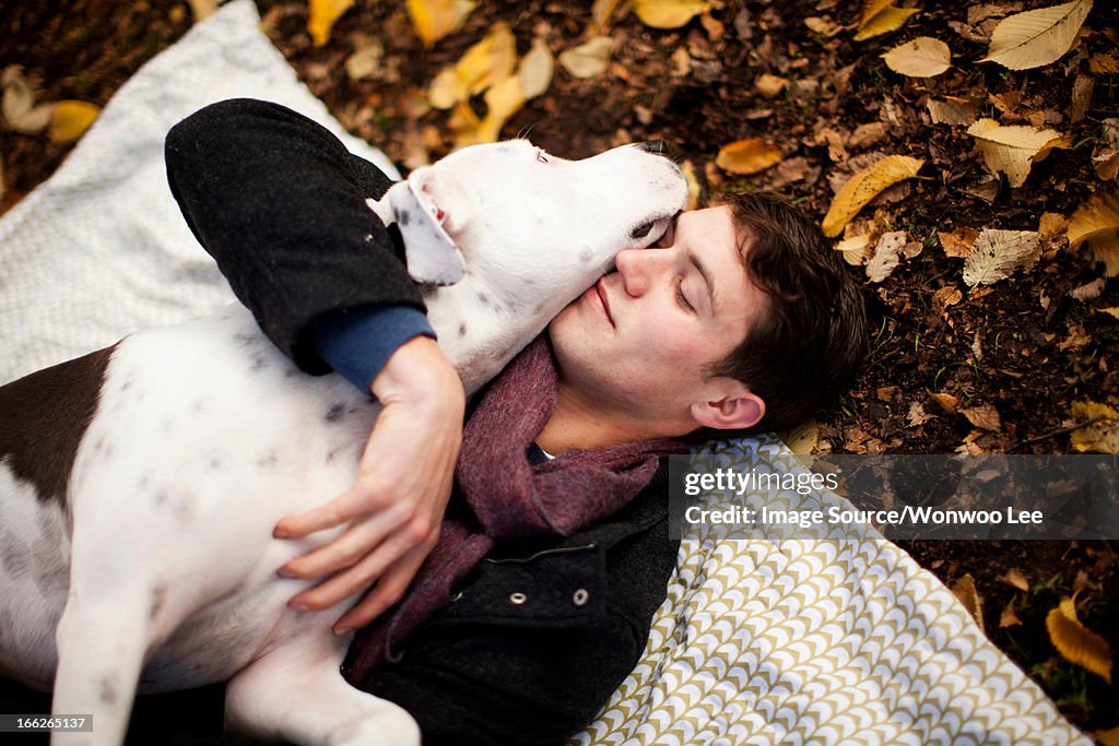 Man and dog hugging on picnic blanket
