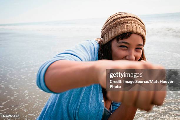 smiling woman making fists on beach - vechtsport stockfoto's en -beelden