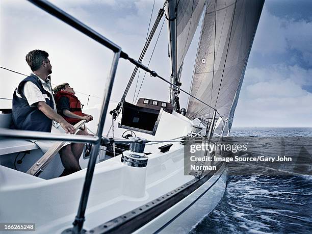 father and son steering boat on water - father son sailing stock pictures, royalty-free photos & images