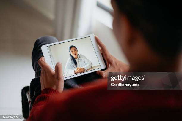 disabled asian man in a wheelchair video conference with doctor on digital tablet - flexible screen stock pictures, royalty-free photos & images