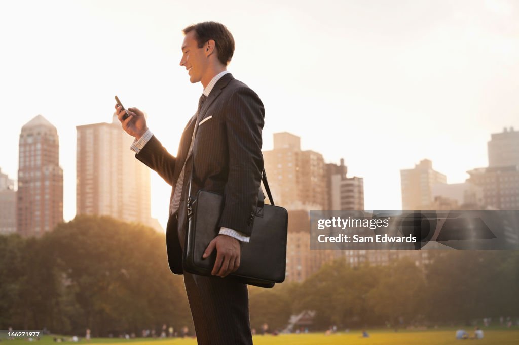 Businessman using cell phone in urban park