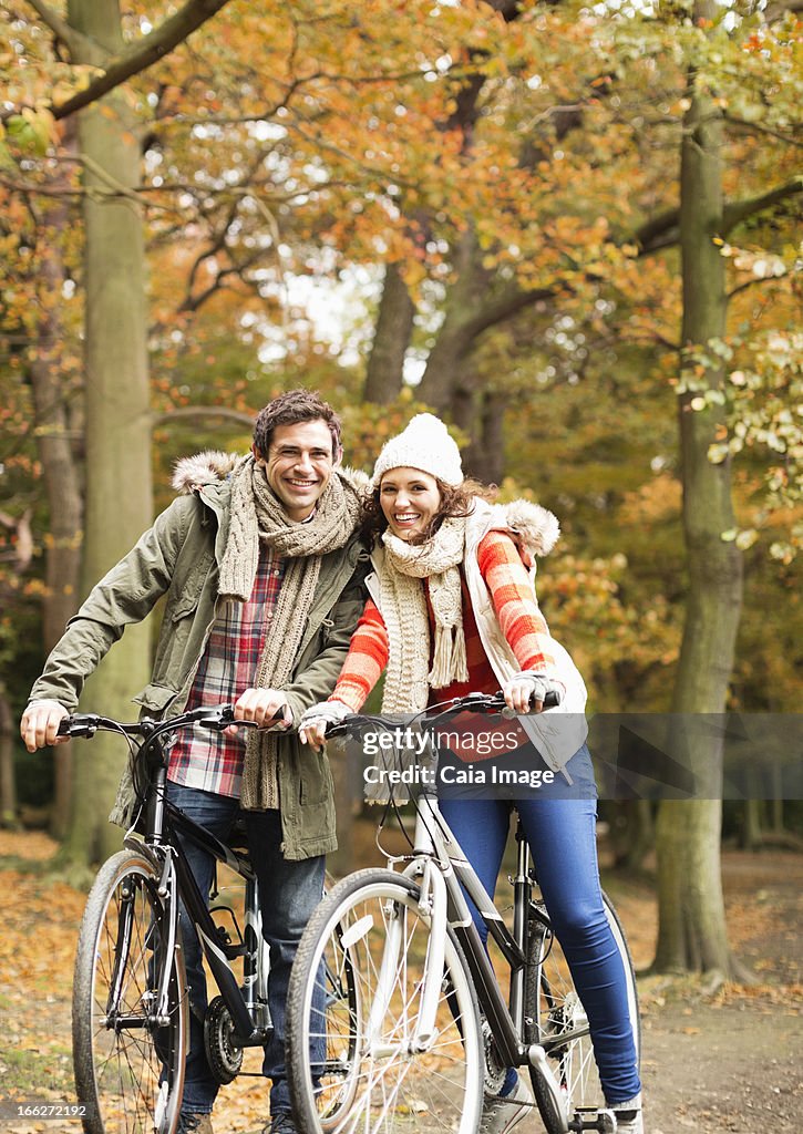 Couple riding bicycles together in park