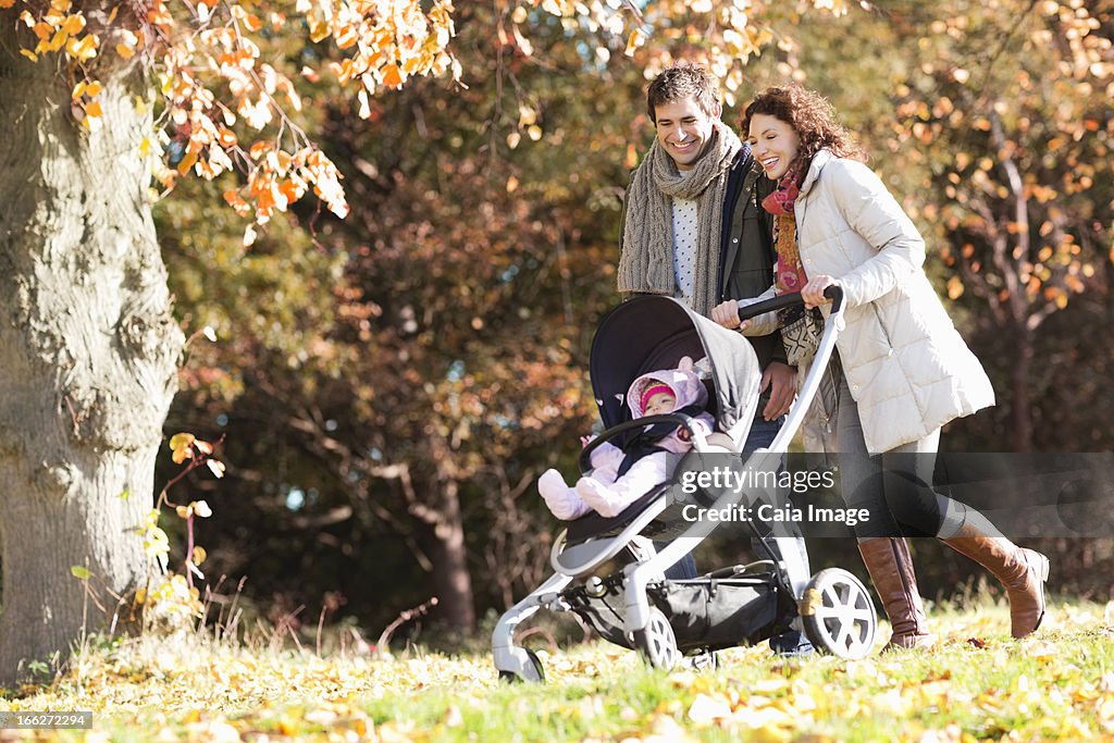 Couple pushing baby in stroller in park