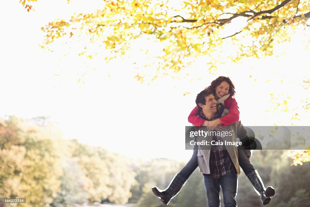 Man carrying girlfriend piggyback in park