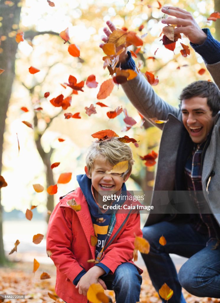 Father and son playing in autumn leaves