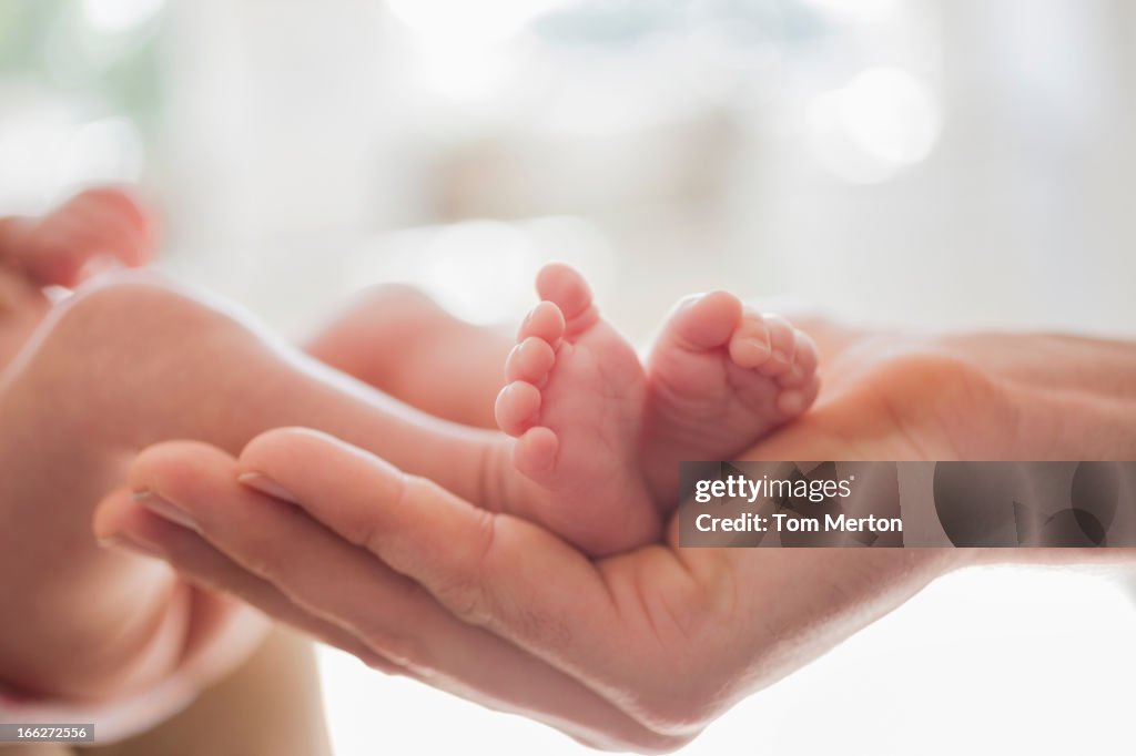 Mother cradling newborn baby's feet