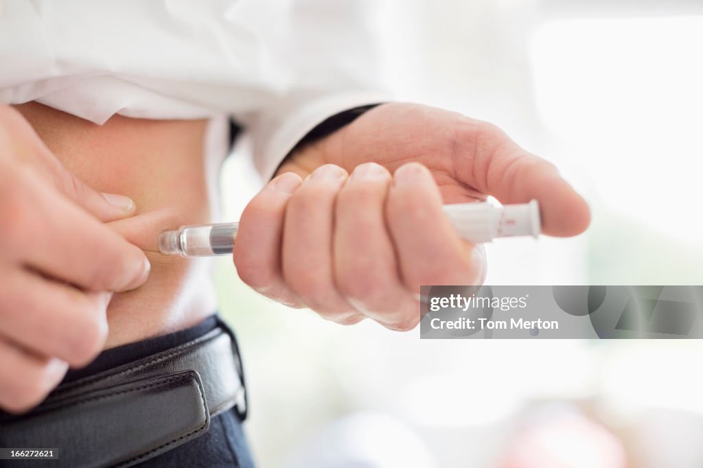 Man giving himself injection in stomach