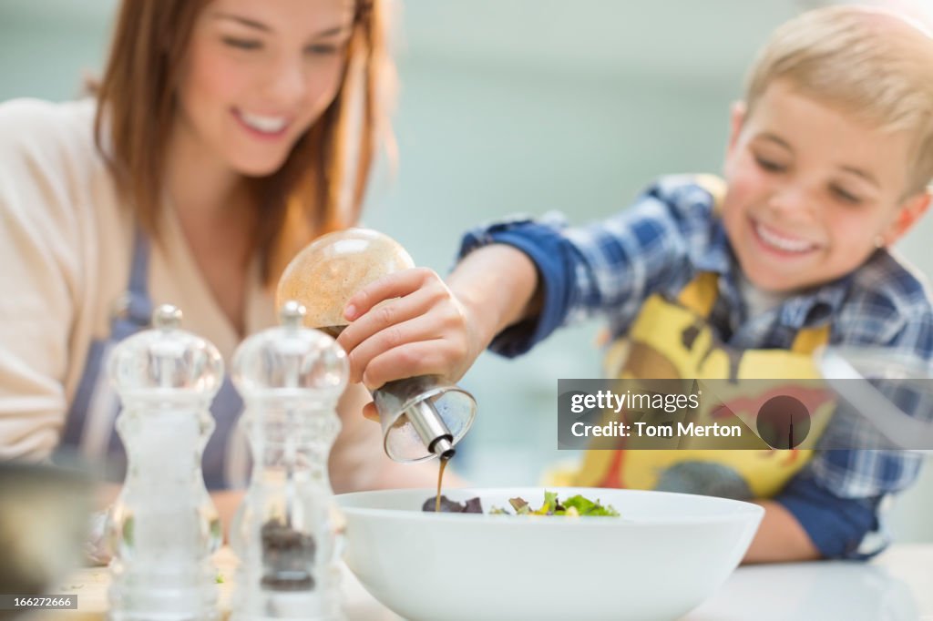 Mother and son making salad in kitchen