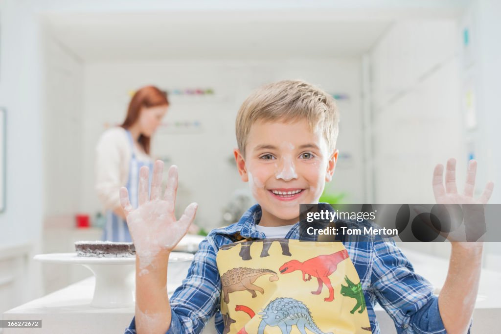 Menino abrangidos em farinha na cozinha