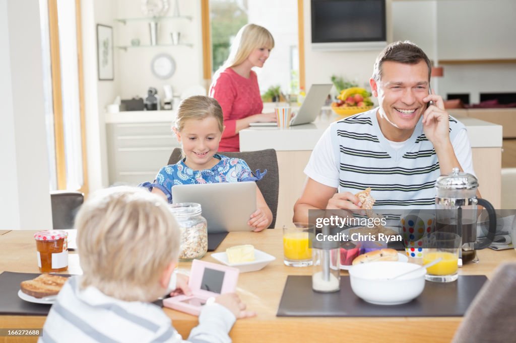 Family using technology at breakfast