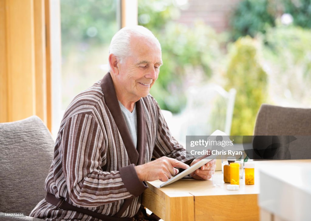 Older man using tablet computer at table