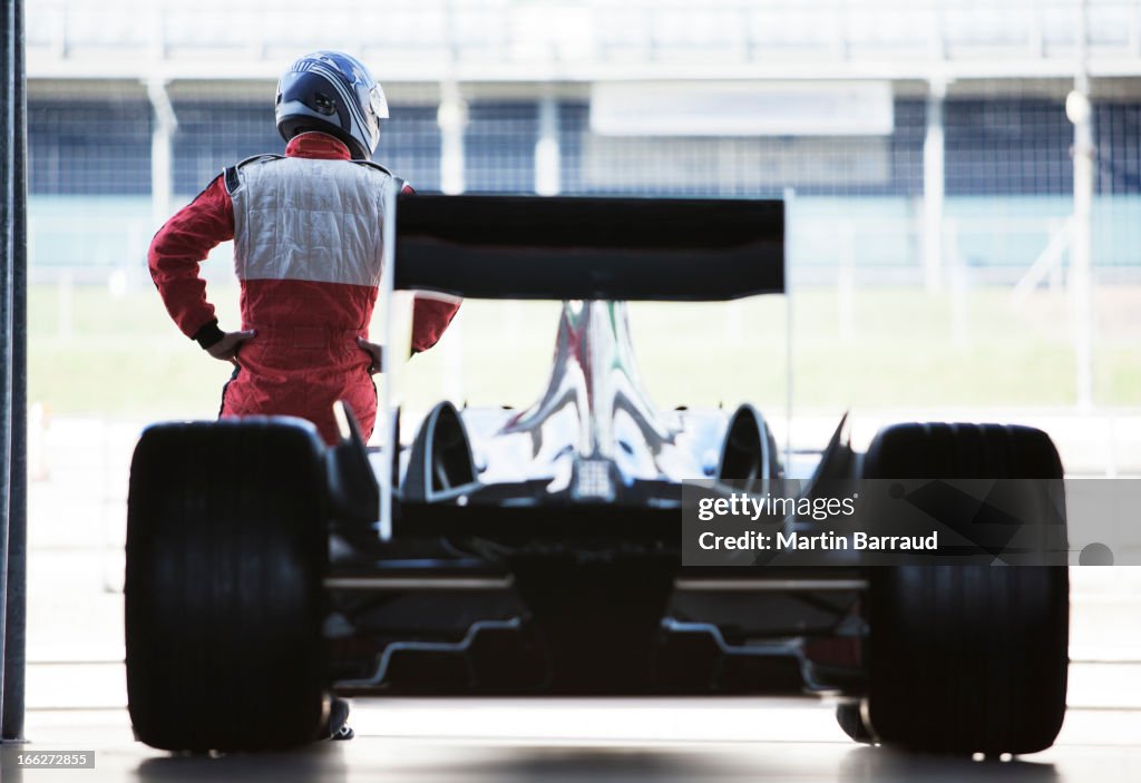 Racer standing with car in garage