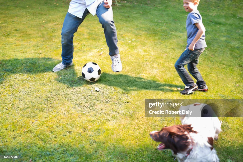 Boy playing soccer with dog outdoors