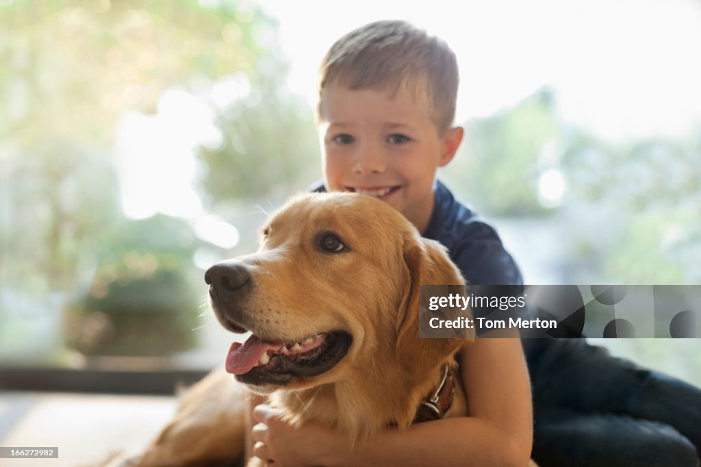 Lächelnden Jungen umarmen Hund im Innenbereich