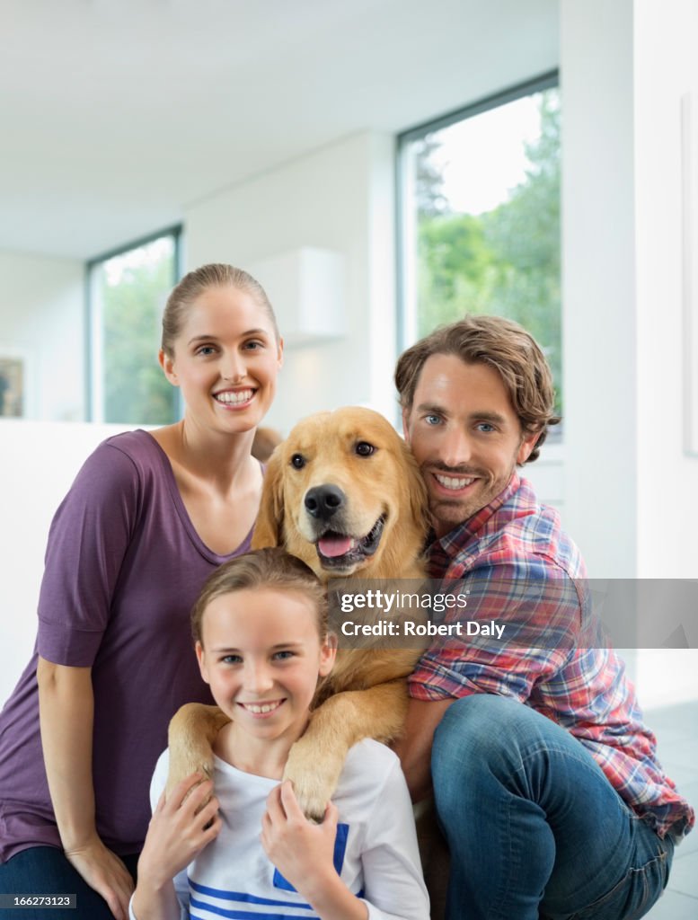 Family smiling with dog indoors