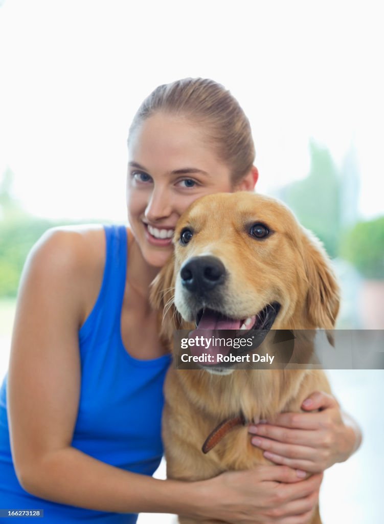 Smiling woman hugging dog indoors