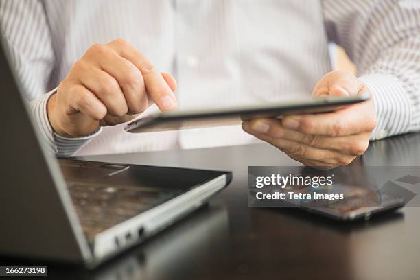 usa, new jersey, jersey city, man using tablet pc, laptop and smartphone - laptop netbook fotografías e imágenes de stock