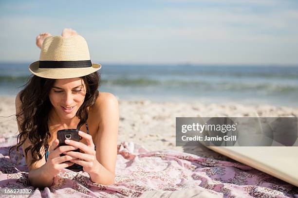 usa, new york state, rockaway beach, woman using cell phone on beach - cell phone using beach stock pictures, royalty-free photos & images