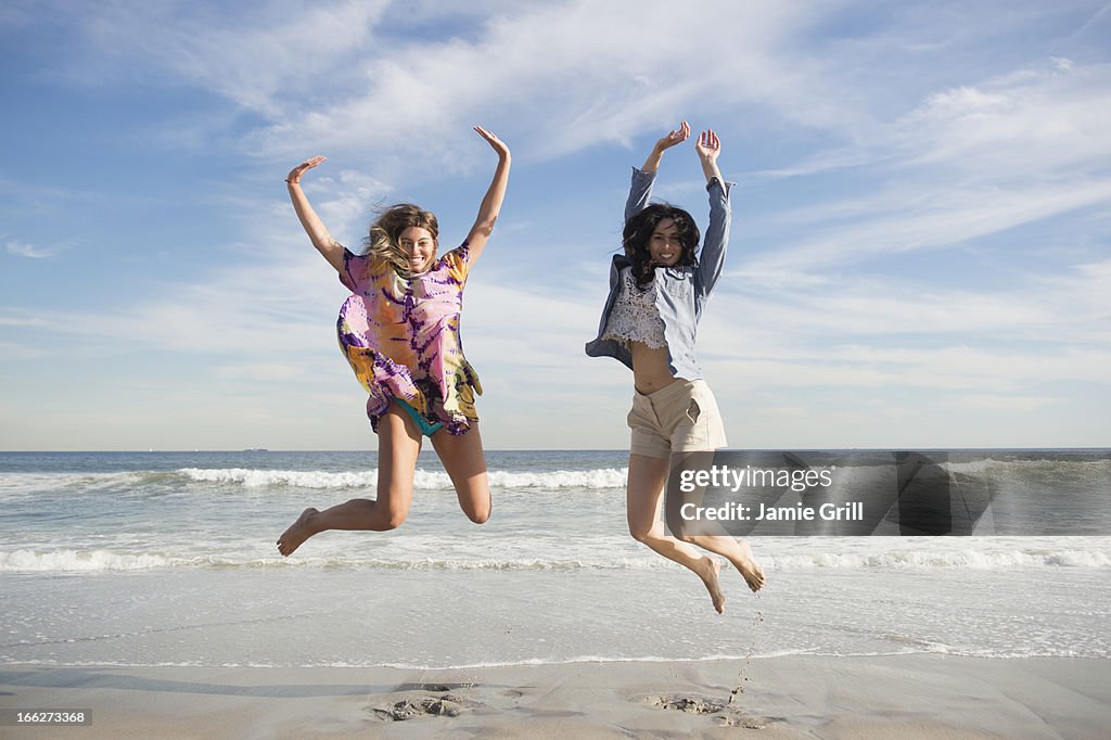 USA, New York State, Rockaway Beach, Two young women jumping on beach