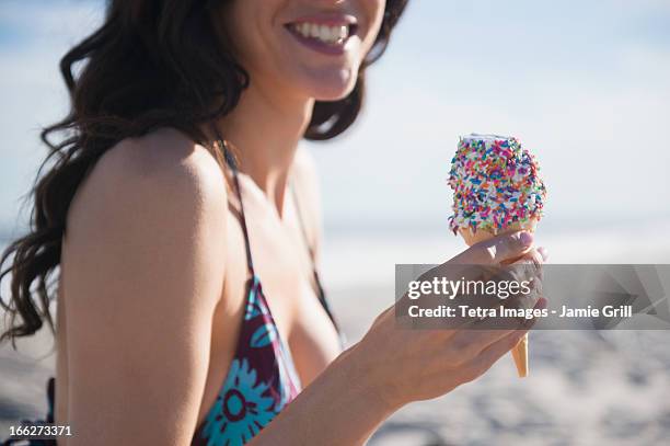 usa, new york state, rockaway beach, woman eating ice-cream on beach - wavy hair beach stock pictures, royalty-free photos & images