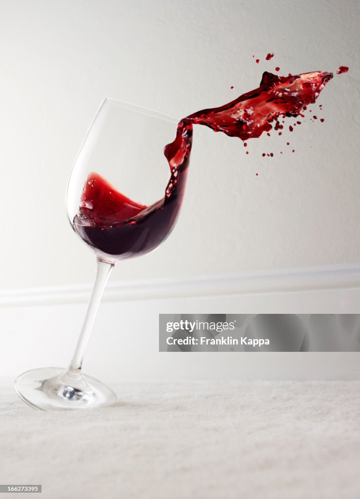 Glass of red wine spilling