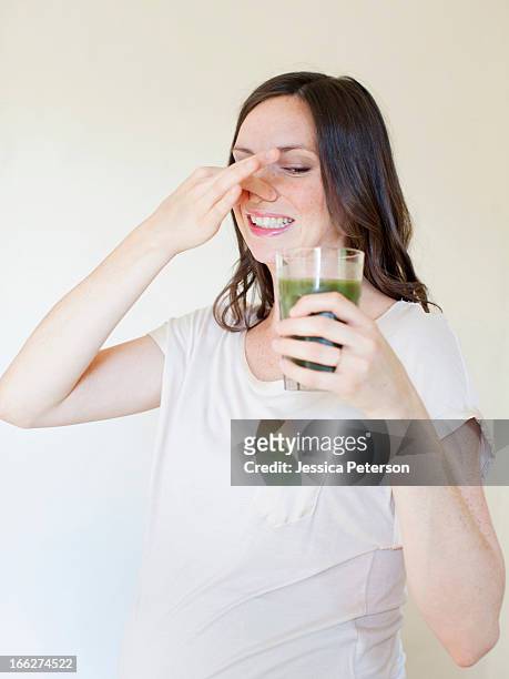 usa, utah, salt lake city, portrait of pregnant mid adult woman drinking green juice - unangenehmer geschmack stock-fotos und bilder