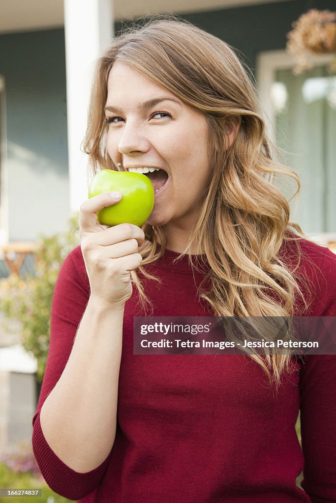 USA, Utah, Provo, Portrait of young woman biting green apple