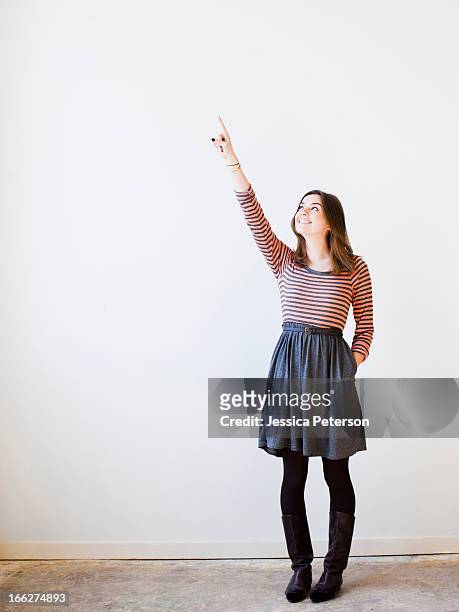 studio shot young woman looking up and pointing - skirt stock pictures, royalty-free photos & images