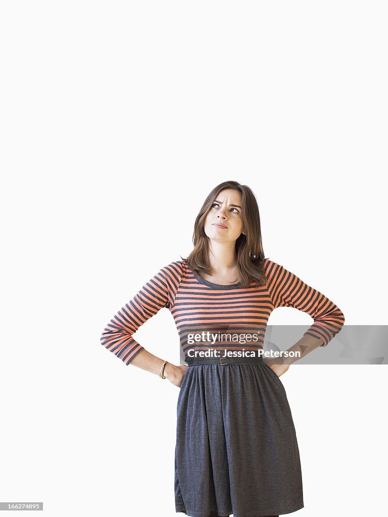 Studio shot young woman with hands on hip looking up