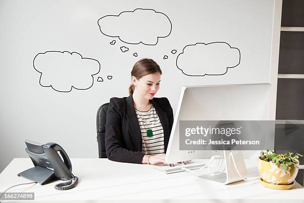 studio shot of young woman working at desk with thought bubbles around her head - thought bubble imagens e fotografias de stock