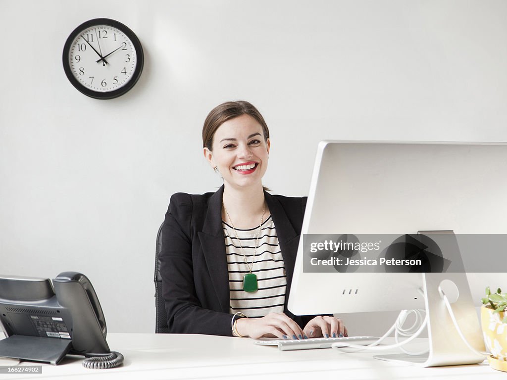Studio shot portrait of young woman working on computer and smiling