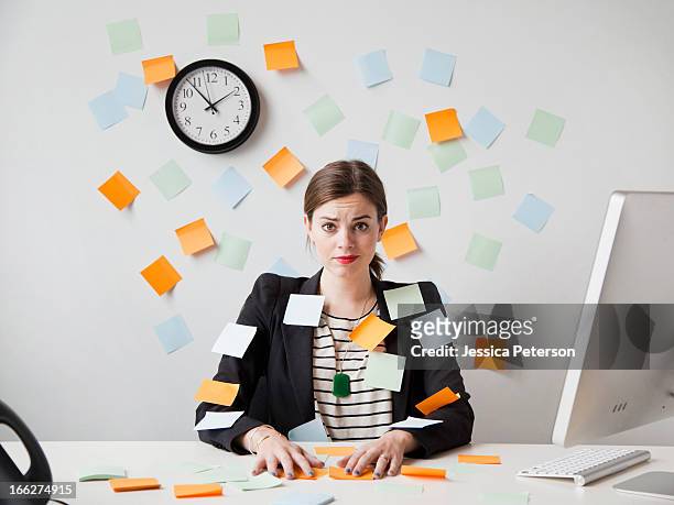 studio shot of young woman working in office covered with adhesive notes - surchargé de travail photos et images de collection