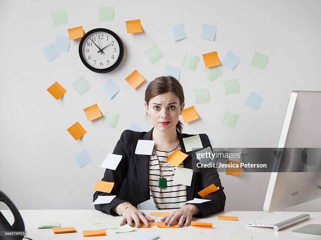 Studio shot of young woman working in office covered with adhesive notes