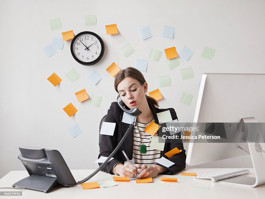 Studio shot of young woman working in office covered with adhesive notes