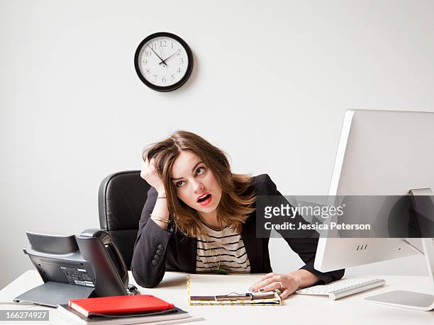 studio shot of young woman working in office being under emotional stress - clock person desk stockfoto's en -beelden