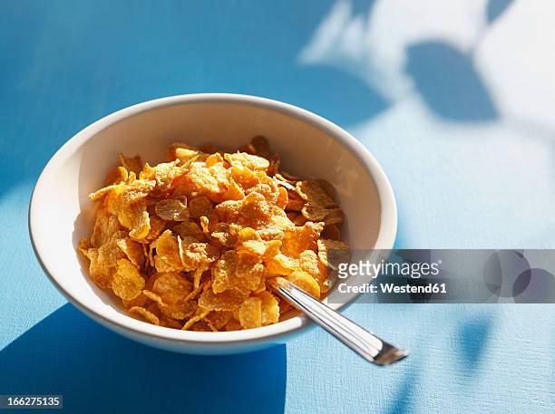 cornflakes and spoon in bowl, close-up - bowl of cereal stock pictures, royalty-free photos & images