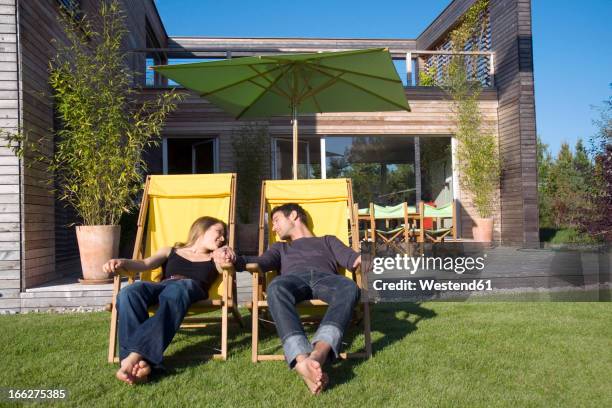 couple sunbathing on loungers - man sitting in recliner stock pictures, royalty-free photos & images