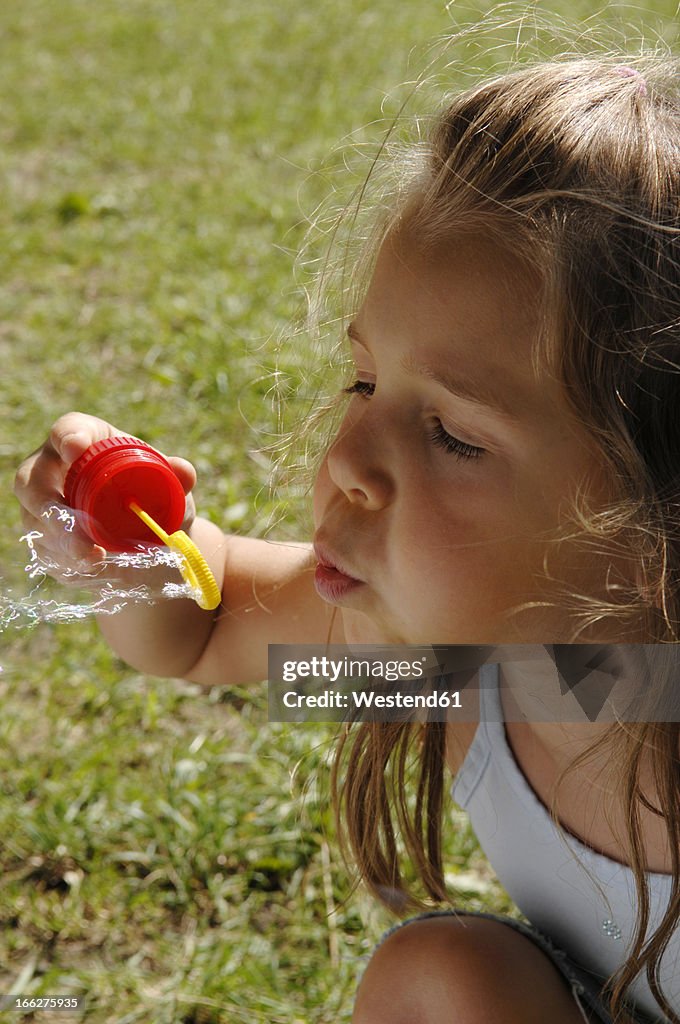 Girl (4-6) blowing bubbles, close-up