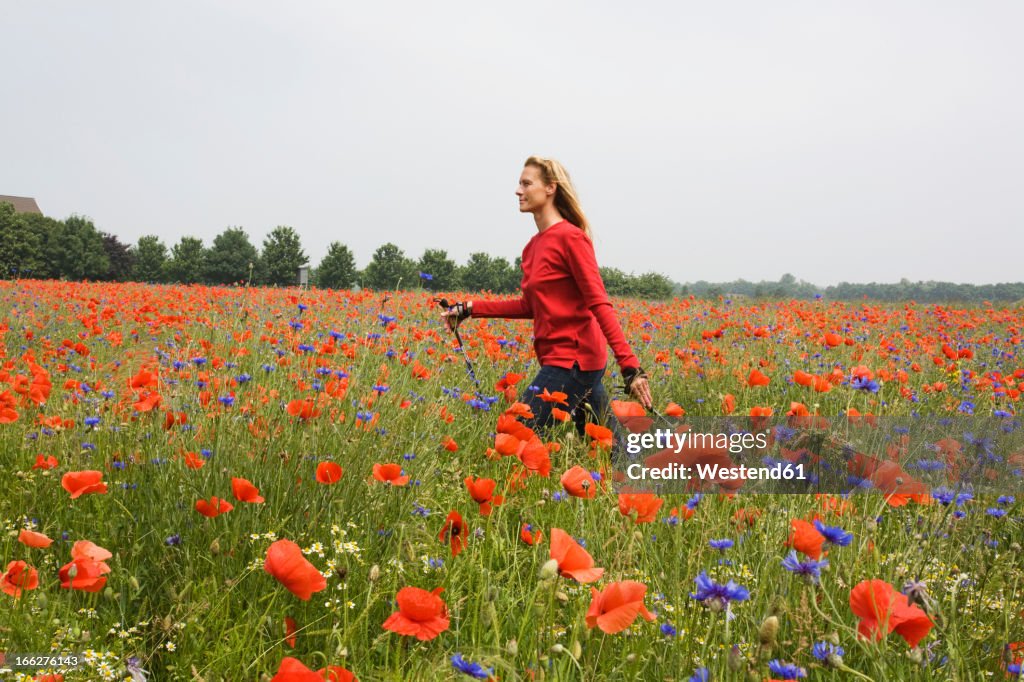 Woman walking across poppy field