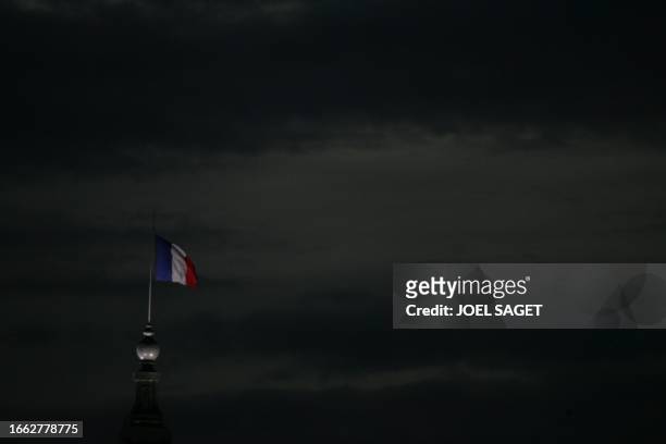 Les nuages au-dessus un drapeau tricolore qui flotte sur le toit du Grand Palais, le 20 octobre 2006, à Paris. AFP PHOTO JOEL SAGET