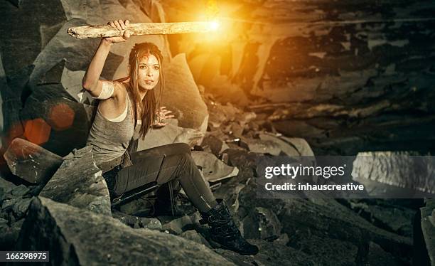 female heroine looking in a cave with torch - cave fire stock pictures, royalty-free photos & images