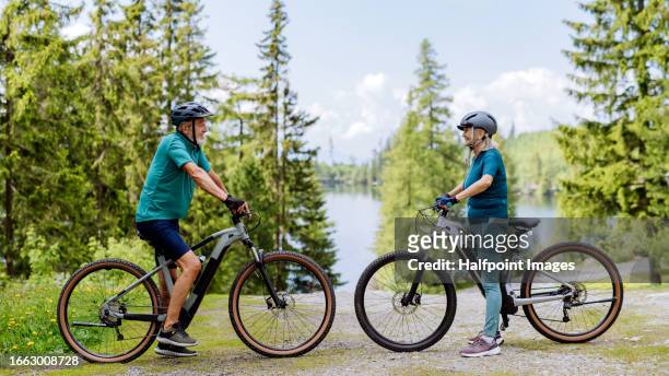 senior couple bike riding in mountains on easy bike trail, during their summer vacation - fahrrad fahren alte leute beine stock-fotos und bilder