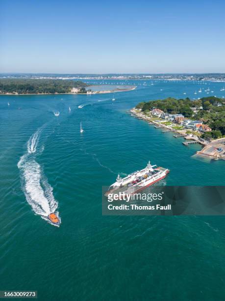 rescue boat passes sandbanks chain ferry in poole harbour - beach rescue aerial stock pictures, royalty-free photos & images