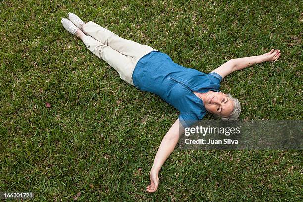 mature woman laying on grass in the backyard - auf dem rücken liegen stock-fotos und bilder